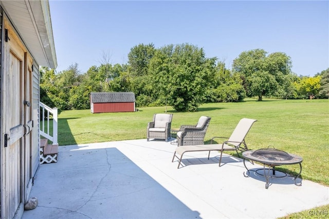 view of patio / terrace featuring an outdoor structure, a fire pit, and a storage unit