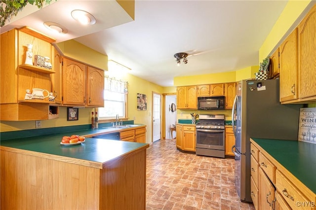 kitchen featuring appliances with stainless steel finishes, a peninsula, brick floor, open shelves, and a sink