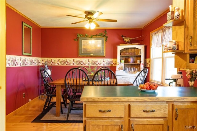 dining room featuring light wood-style flooring, ornamental molding, and a ceiling fan