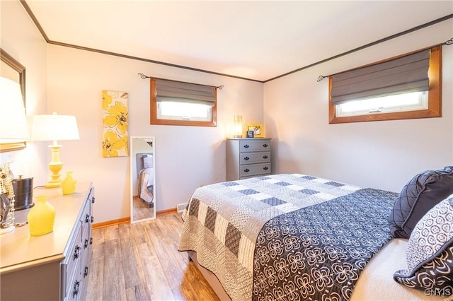 bedroom featuring light wood-style flooring, multiple windows, and crown molding