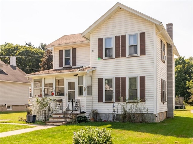 view of front facade featuring central AC, a chimney, a front yard, and a sunroom