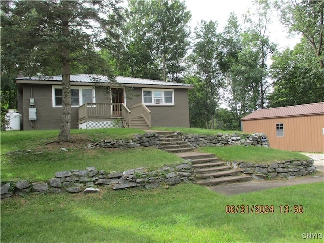 view of front facade featuring a front yard, stucco siding, and metal roof