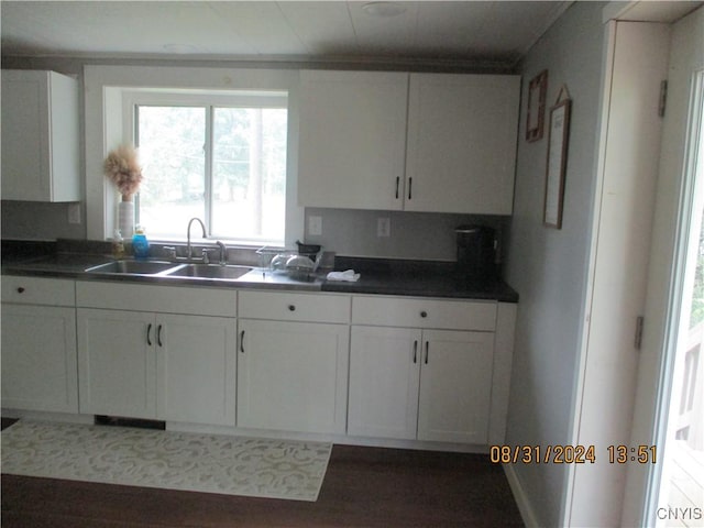kitchen with dark countertops, white cabinets, and a sink