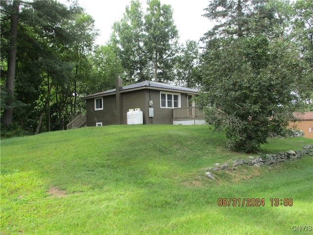 view of front facade with a wooden deck and a front yard