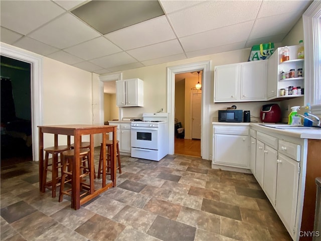 kitchen with white cabinetry, gas range gas stove, and a drop ceiling