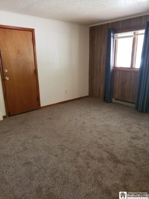 spare room featuring a baseboard heating unit, carpet, and a textured ceiling