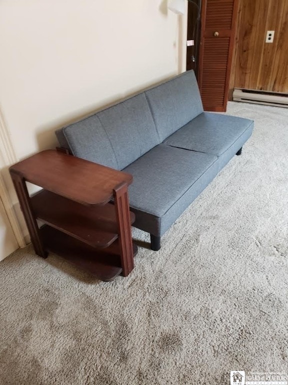 sitting room with baseboard heating, wood walls, and carpet