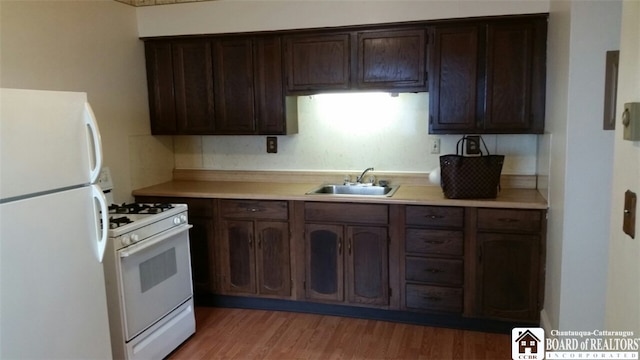 kitchen featuring white appliances, hardwood / wood-style flooring, dark brown cabinets, and sink