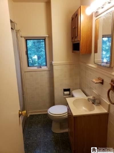 bathroom with tile patterned floors, vanity, toilet, and tile walls