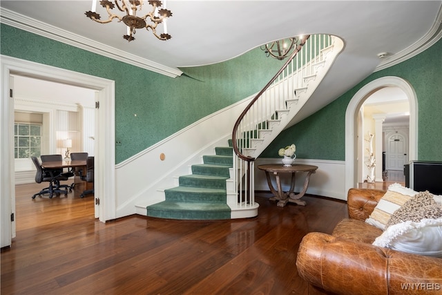 staircase featuring hardwood / wood-style floors, an inviting chandelier, and crown molding