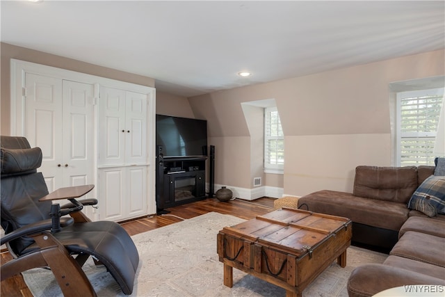 living room with lofted ceiling, plenty of natural light, and hardwood / wood-style floors