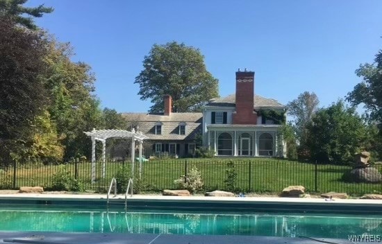 rear view of house with a yard, a fenced in pool, and a pergola