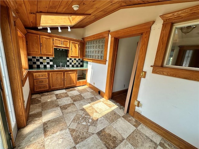 kitchen featuring wood ceiling, brown cabinets, a sink, and backsplash