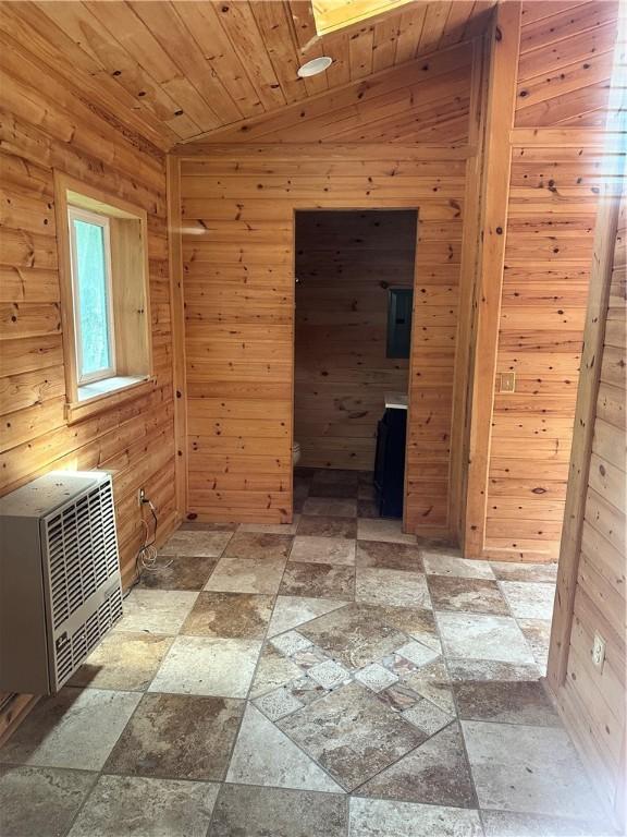 spare room with stone tile floors, heating unit, lofted ceiling, wooden walls, and wooden ceiling