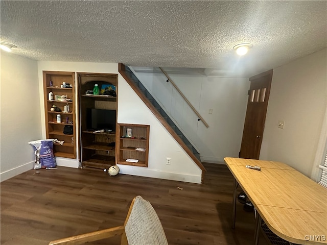 interior space with built in shelves, dark hardwood / wood-style floors, and a textured ceiling