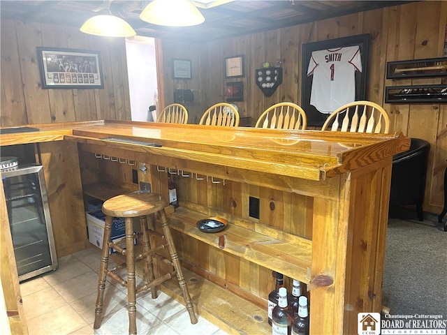 bar featuring beverage cooler, wood walls, and light tile patterned flooring