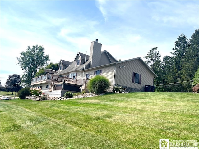 back of property featuring a wooden deck and a lawn