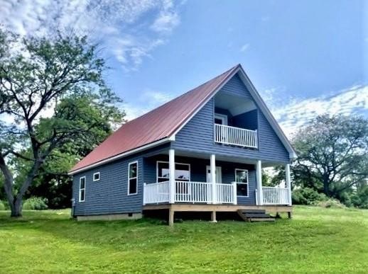 rear view of property featuring a balcony, a porch, and a lawn