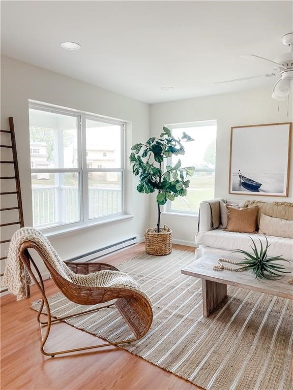 sitting room featuring a baseboard heating unit, ceiling fan, and hardwood / wood-style floors