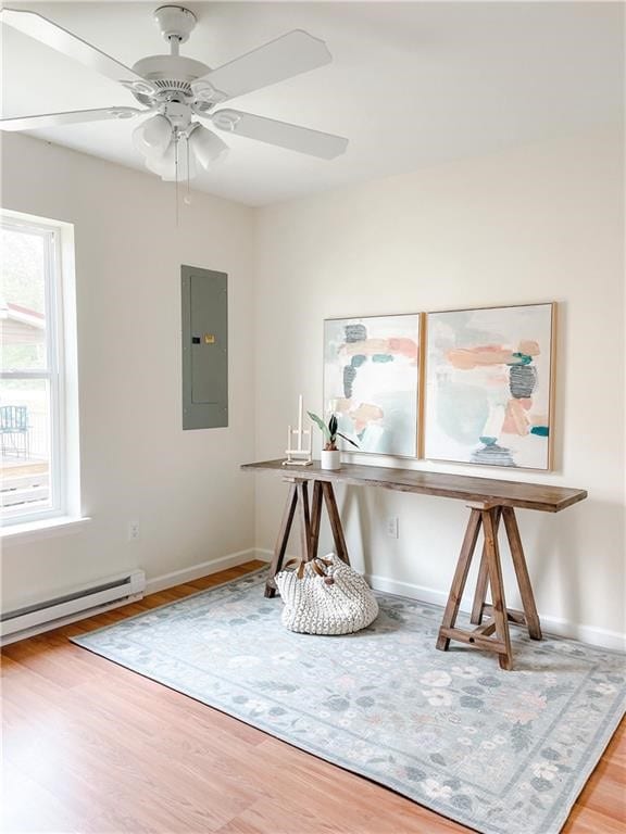 interior space featuring ceiling fan, electric panel, baseboard heating, and hardwood / wood-style flooring