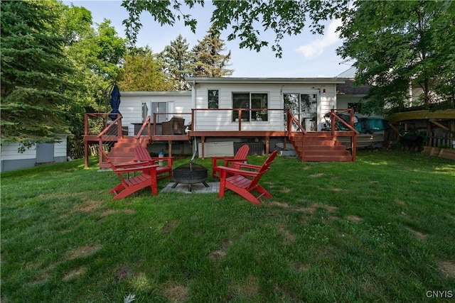 rear view of property with a lawn, a fire pit, a wooden deck, and stairs