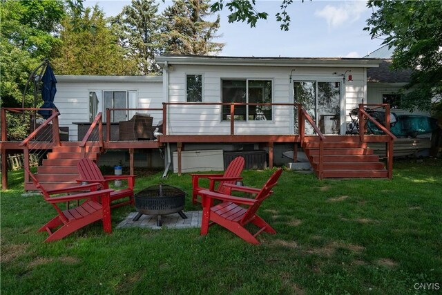 back of property with a wooden deck, a lawn, and an outdoor fire pit