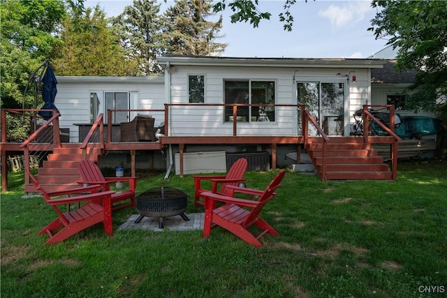 back of property with a wooden deck, stairs, a fire pit, and a yard