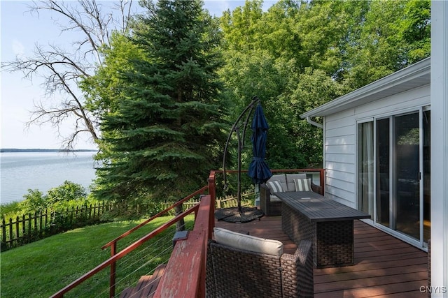 wooden terrace featuring a lawn, a water view, and fence