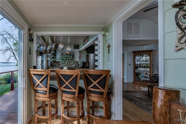 bar featuring freestanding refrigerator, a healthy amount of sunlight, visible vents, and wood finished floors