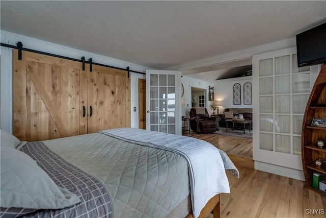 bedroom featuring a textured ceiling, a barn door, and hardwood / wood-style flooring