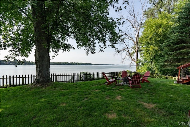 view of yard with a water view, an outdoor fire pit, and fence