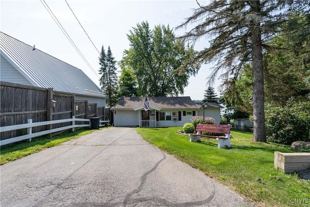 view of front of house with aphalt driveway, a garage, fence, and a front lawn