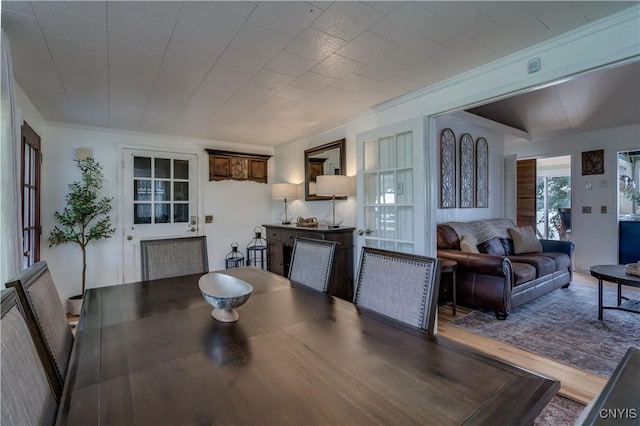 dining space featuring wood finished floors and crown molding