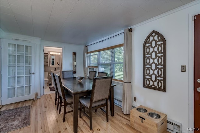 dining area with a baseboard heating unit and light wood-type flooring