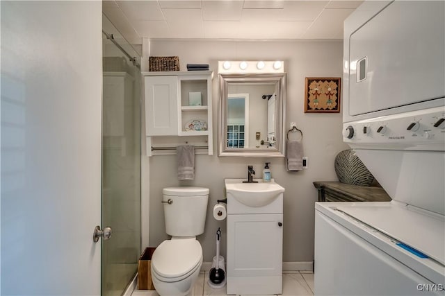 bathroom featuring stacked washer and dryer, toilet, a shower with shower door, vanity, and baseboards