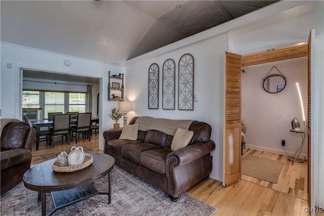 living area featuring vaulted ceiling, light wood-type flooring, and baseboards