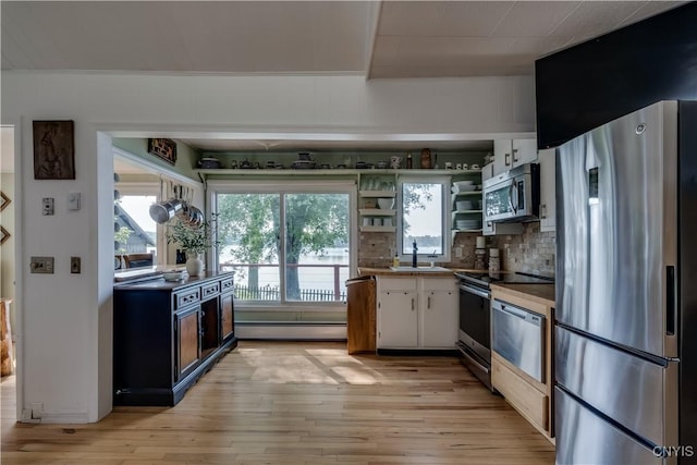 kitchen featuring a sink, appliances with stainless steel finishes, decorative backsplash, open shelves, and light wood finished floors