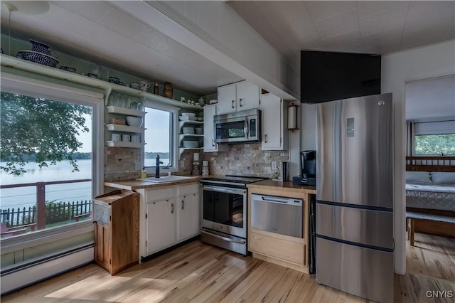 kitchen featuring stainless steel appliances, a sink, white cabinetry, baseboard heating, and open shelves