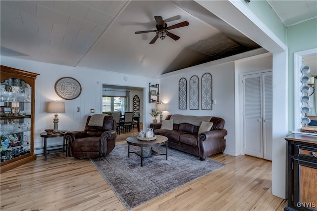 living room with ceiling fan, light hardwood / wood-style floors, and vaulted ceiling