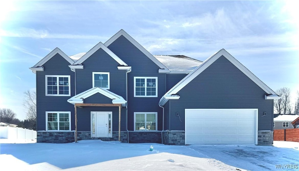 view of front facade with stone siding, an attached garage, and fence