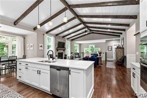kitchen with lofted ceiling with beams, light countertops, white cabinetry, a sink, and stainless steel dishwasher