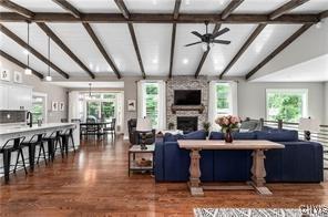 living room with dark wood-style floors, lofted ceiling with beams, ceiling fan, and a large fireplace