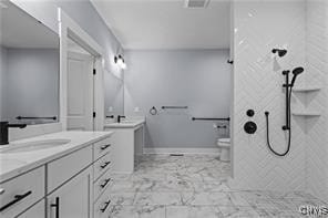 bathroom with tiled shower, vanity, and toilet