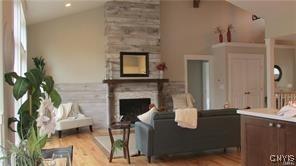 living room featuring a large fireplace, vaulted ceiling, and light wood-type flooring