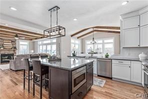 kitchen with light wood finished floors, open floor plan, a kitchen bar, and appliances with stainless steel finishes