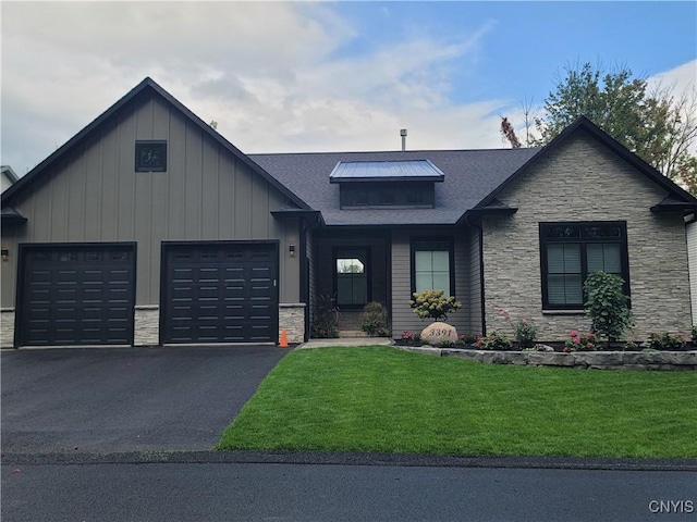 view of front of house featuring stone siding, driveway, a front lawn, and an attached garage
