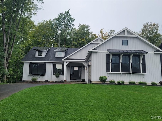 modern farmhouse style home featuring a shingled roof, a standing seam roof, aphalt driveway, and a front lawn