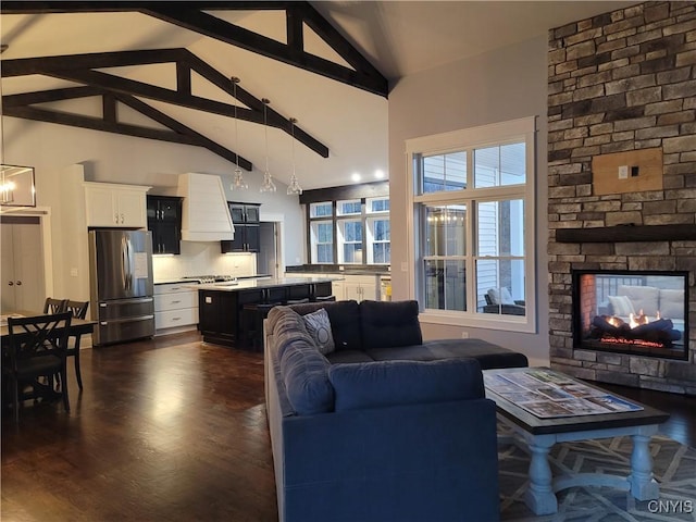 living room featuring dark wood-style flooring, a fireplace, high vaulted ceiling, and beamed ceiling