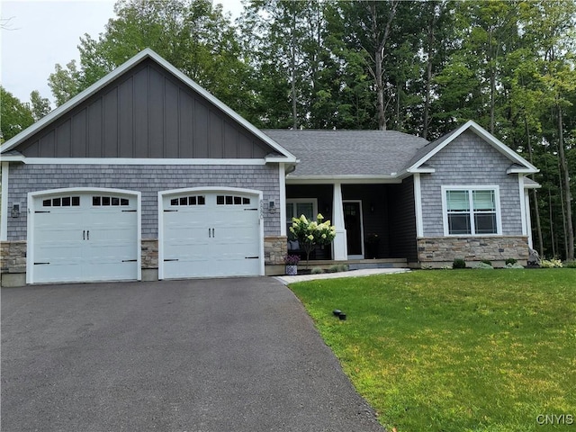 craftsman-style home featuring stone siding, aphalt driveway, an attached garage, and a front yard