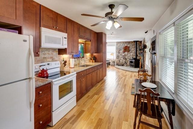 1090 Park Hill Rd, Colchester, NY 13755 - kitchen with a ceiling fan, a wood stove, a sink, white appliances, and light wood-style flooring